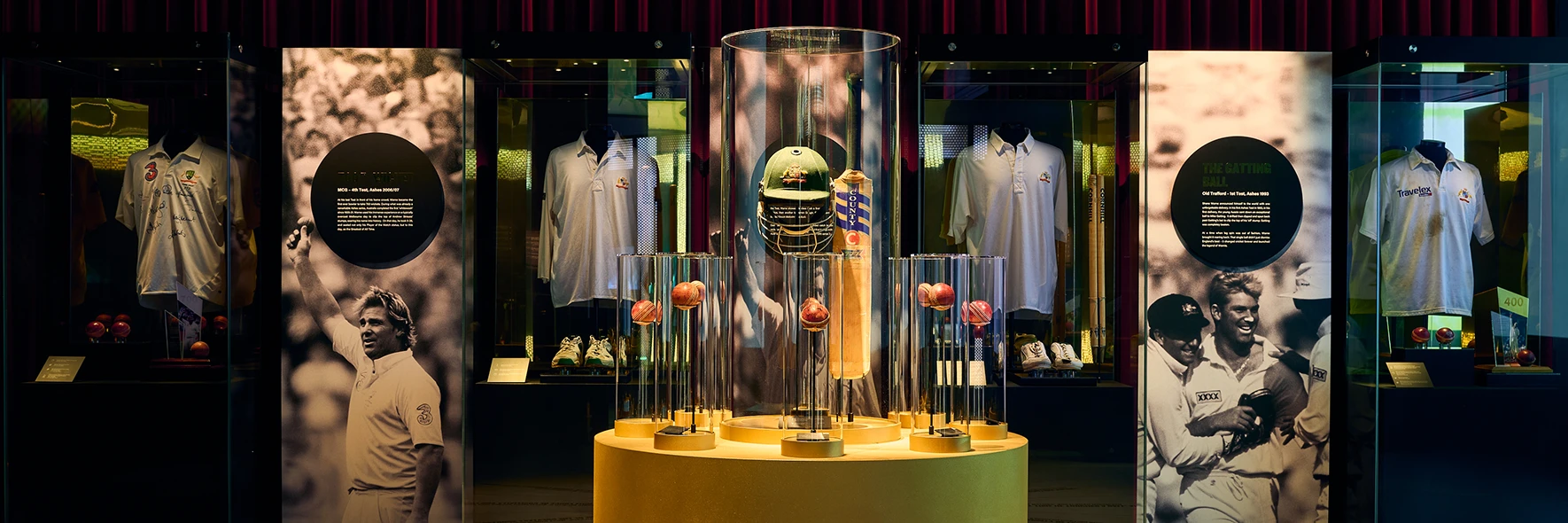 Shane Warne exhibition with cricket balls in a golden centre, surrounded by glass displays and red curtains.
