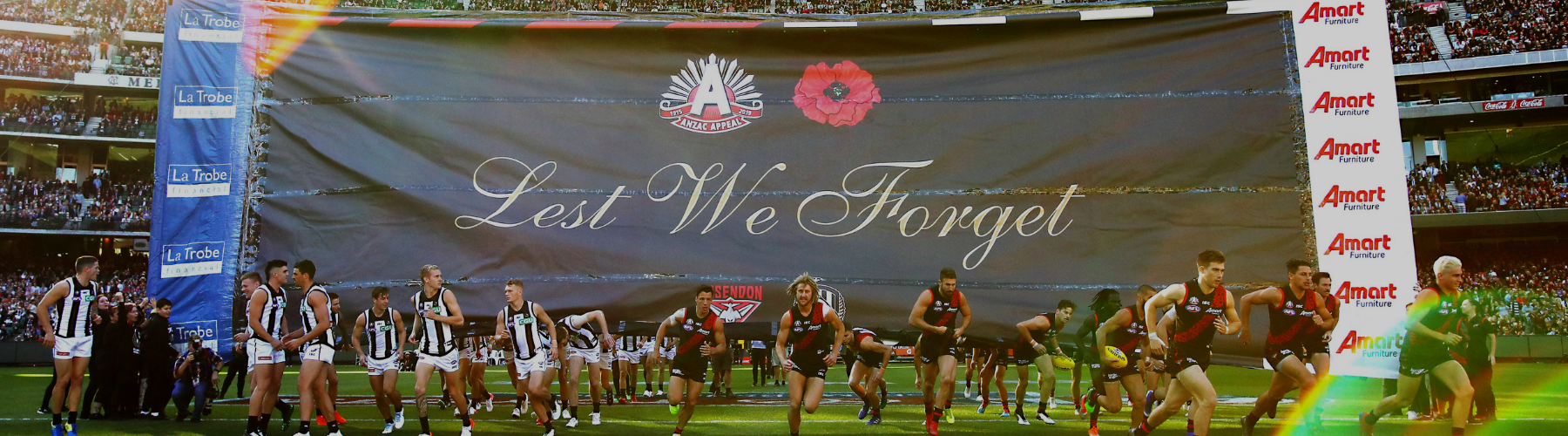 Essendon and Collingwood run through the ANZAC Day banner