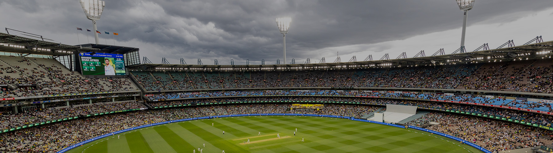 A wide view of the MCG cricket pitch with the stands and light towers in the background