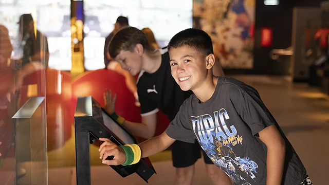 Child interacting with museum display and smiling
