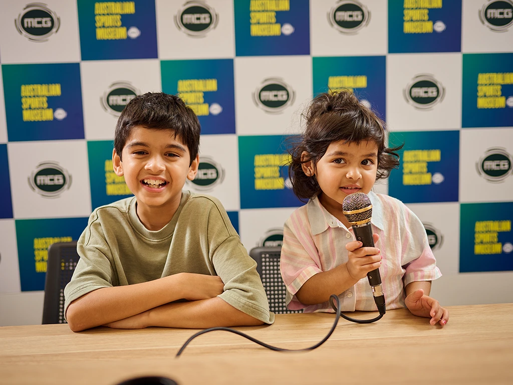 Two children pose at a mock MCG press conference