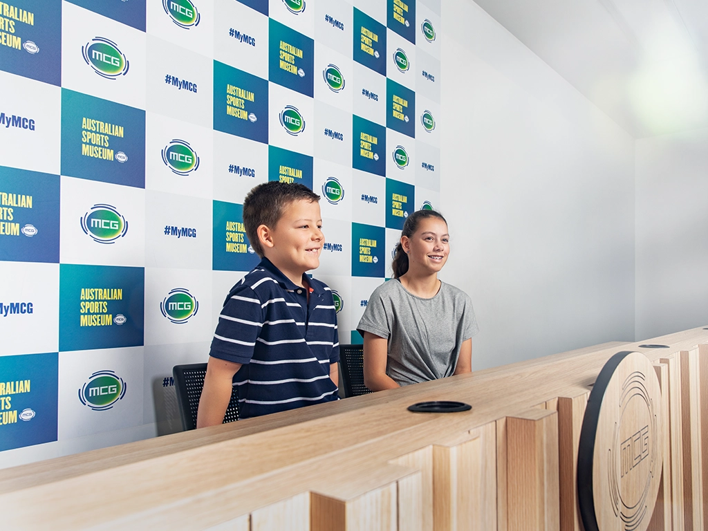 MCG Premium Access Tour Two kids sit in the MCG media conference room during a Premium Access Tour