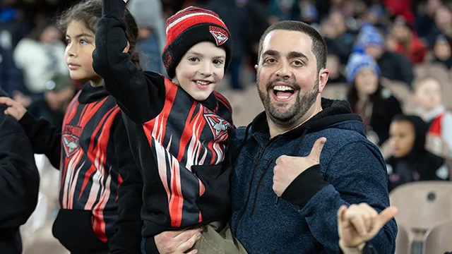 Guardian with young children enjoying an AFL match.