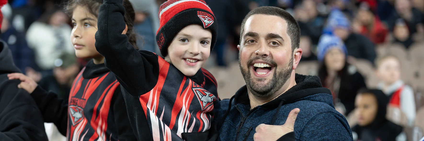 Guardian with young children enjoying an AFL match.