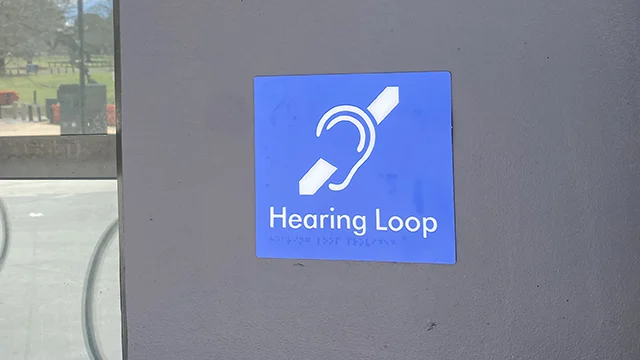 Hearing Loop sign with braille on a wall