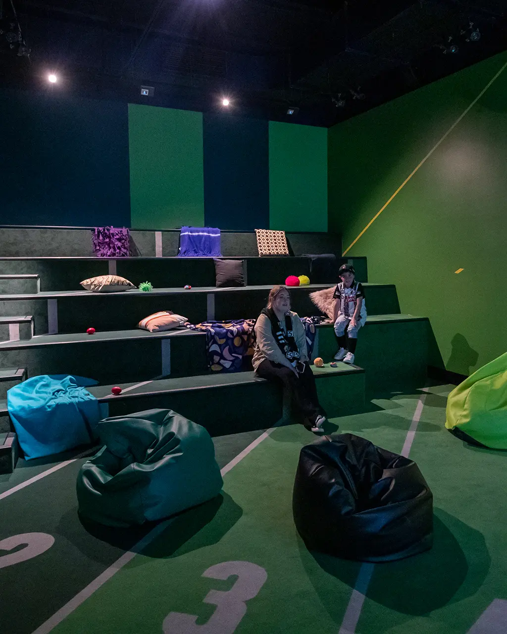 Inside sensory space with beanbags, pillows, fidgets, tiered seating and cinema lighting.