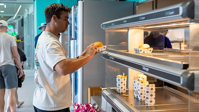 A patron selects a burger from the MCG Food Store A patron selects a burger from the MCG Food Store