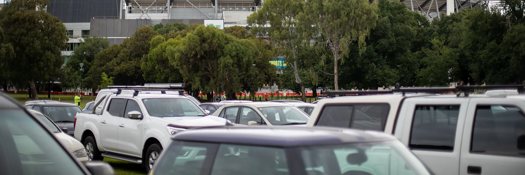 Cars parked in parkland in front of the stadium