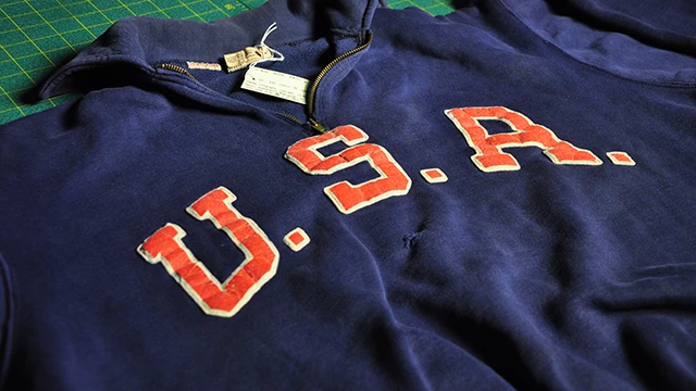 Vintage USA tracksuit top with red appliqué lettering, laid flat for cataloguing