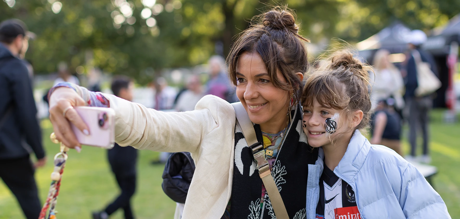 Adult and young Collingwood fan with facepaint take a selfie