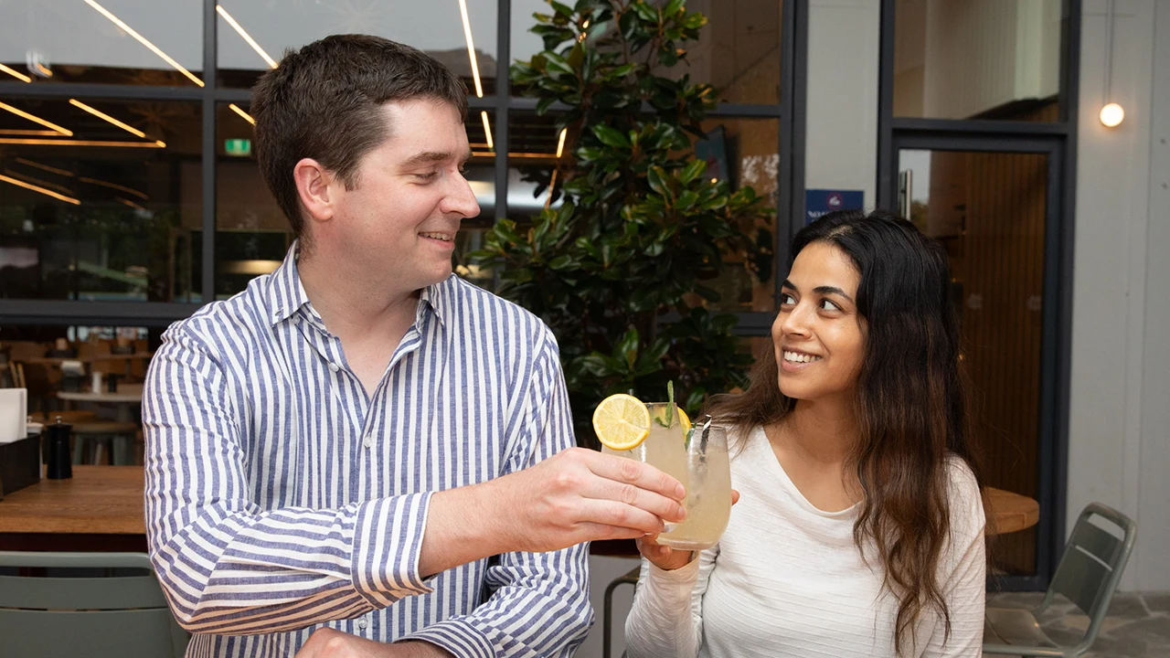 Two people smile and cheers with a summer spritz